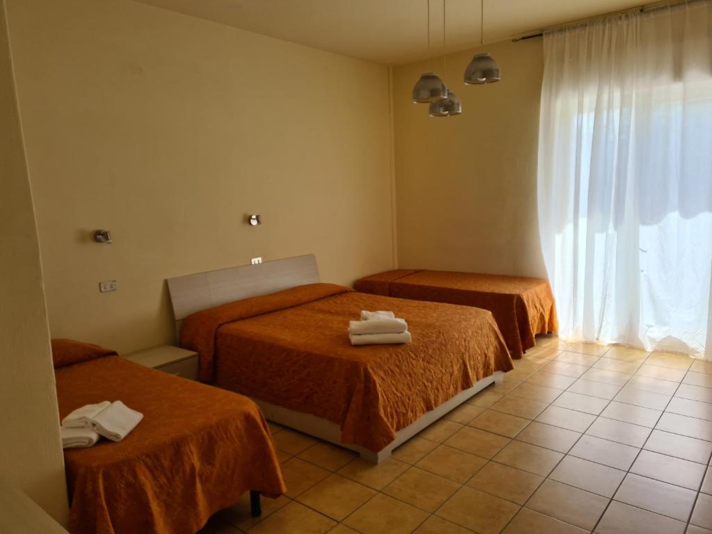 Cette chambre comprend 2 lits avec des draps orange et une fenêtre. dans l'établissement NEW PARK HOTEL, à Lido di Camaiore