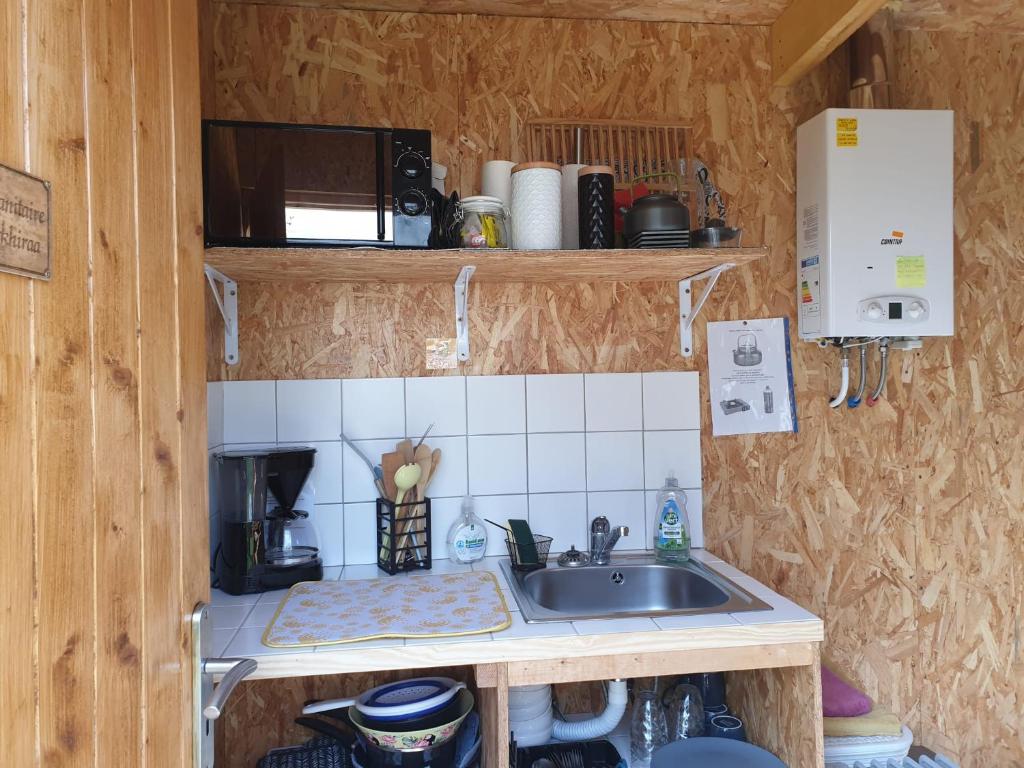 une petite cuisine avec un évier et un micro-ondes dans l'établissement Yourtes 6 personnes proche provins et disney, à Bannost