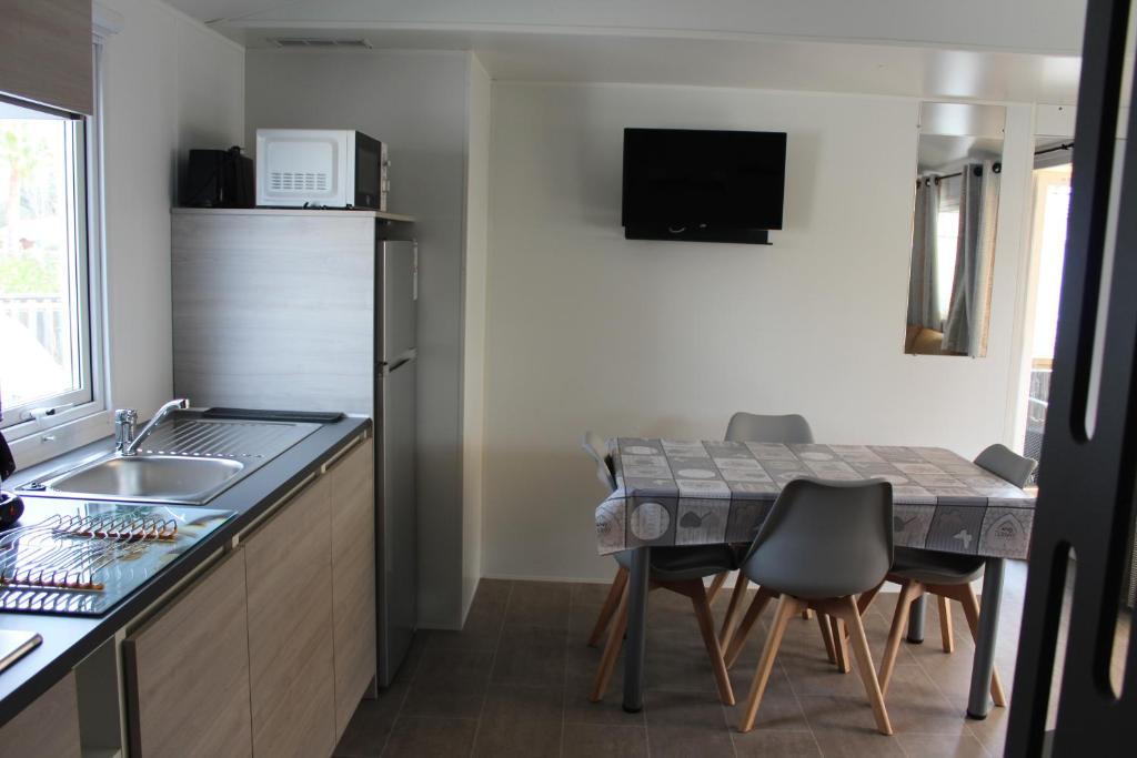 une cuisine avec un évier et une table avec des chaises dans l'établissement Vos meilleures vacances au Montourey!, à Fréjus