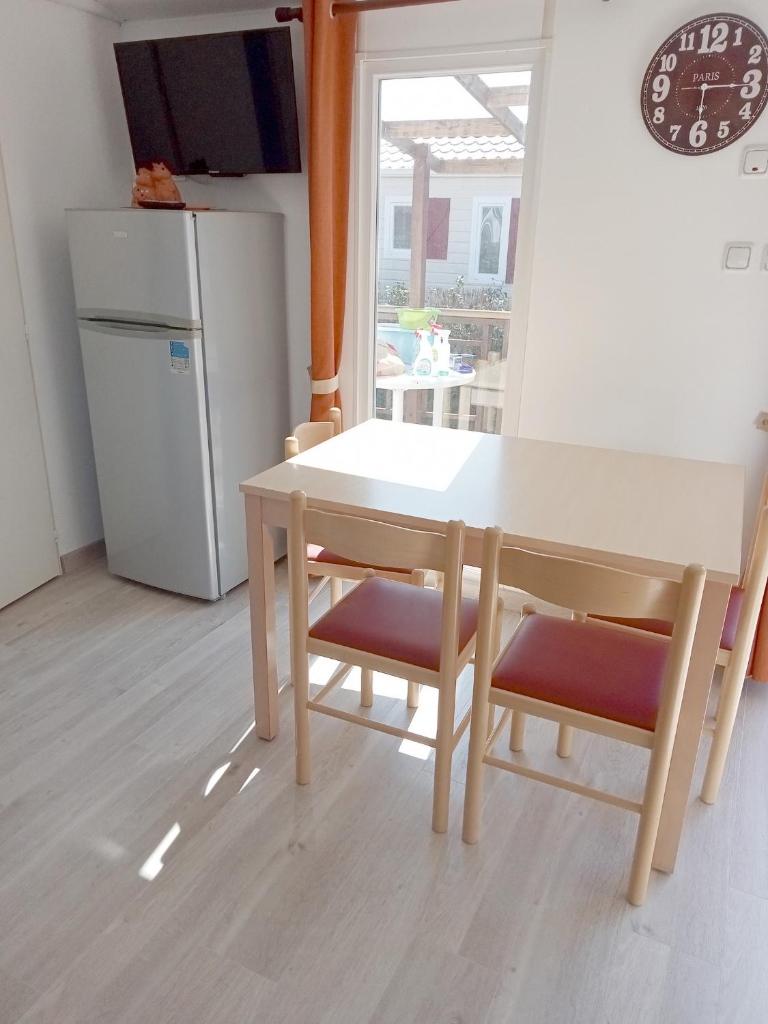La cuisine est équipée d'une table, de deux chaises et d'un réfrigérateur. dans l'établissement Spacieux Mobil-Home Fréjus, à Fréjus