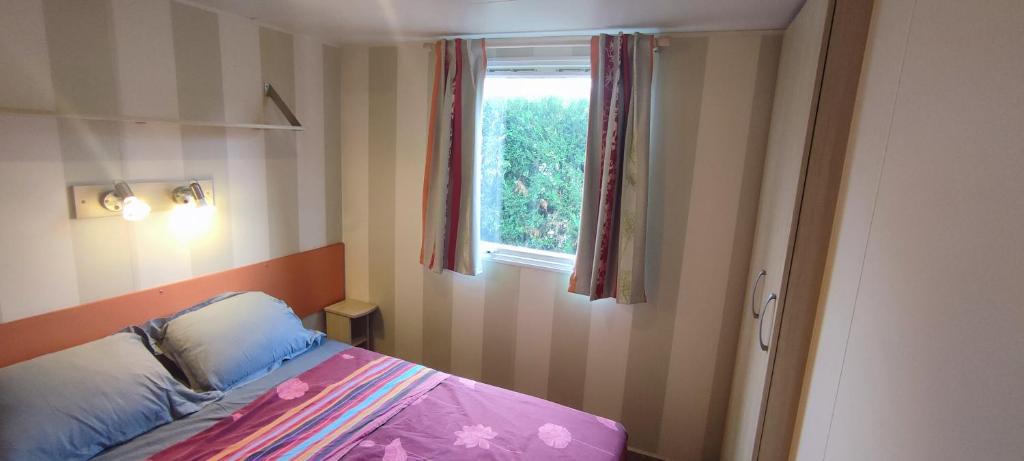 une petite chambre avec un lit et une fenêtre dans l'établissement Mobil home 6 places, à La Roque-dʼAnthéron