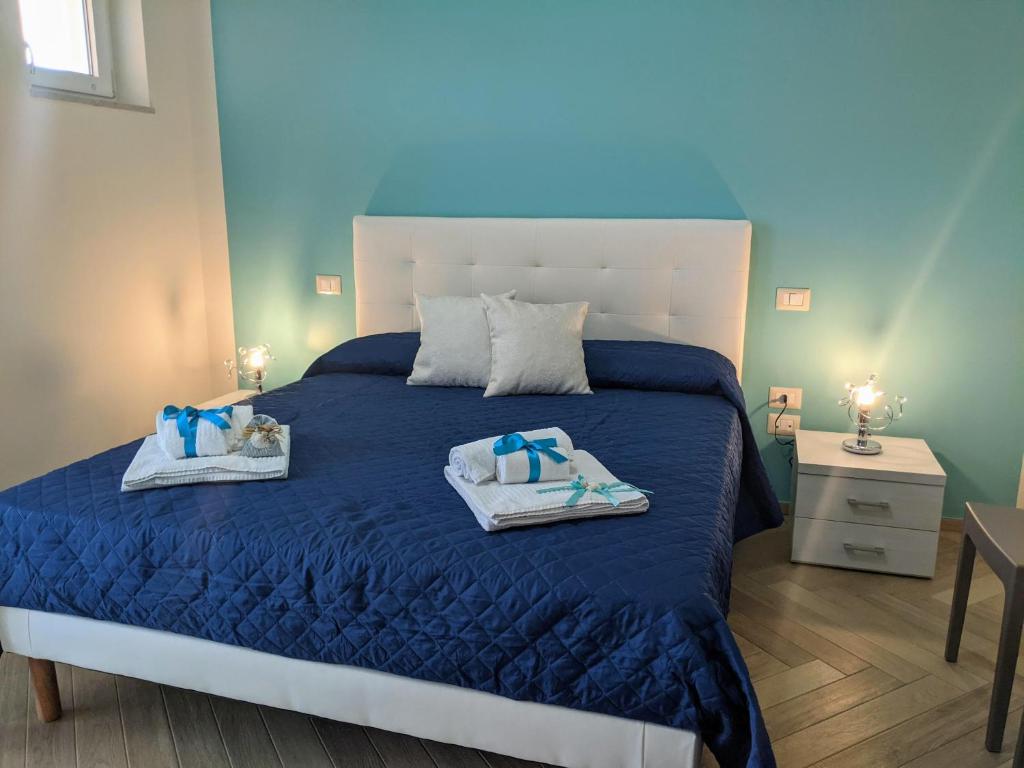 une chambre avec un lit bleu avec deux serviettes dessus dans l'établissement Il Giglio Marino Cilento Residence by ElodeaGroup, à Ascea