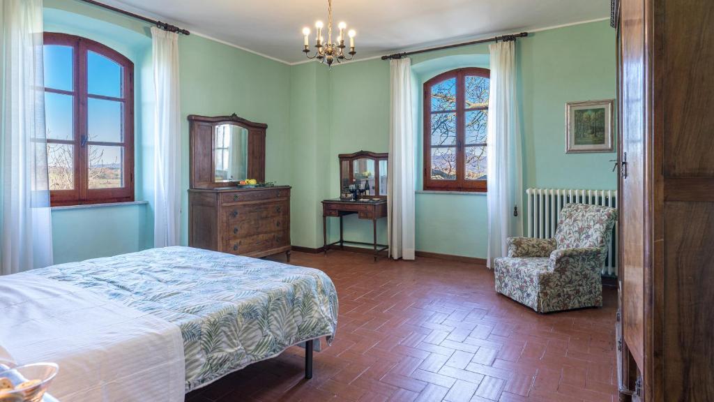 une chambre avec un lit, une chaise et des fenêtres dans l'établissement CASALE LE TRE QUERCE 8&1, Emma Villas, à Orvieto