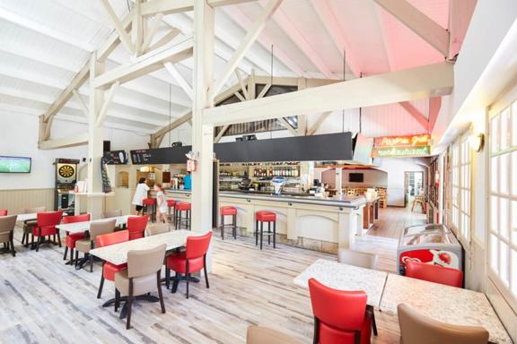 un restaurant avec des chaises rouges, des tables et un comptoir dans l'établissement Charmant mobile-home 6 personnes - Camping 4 étoiles, à Saint-Jean-de-Monts