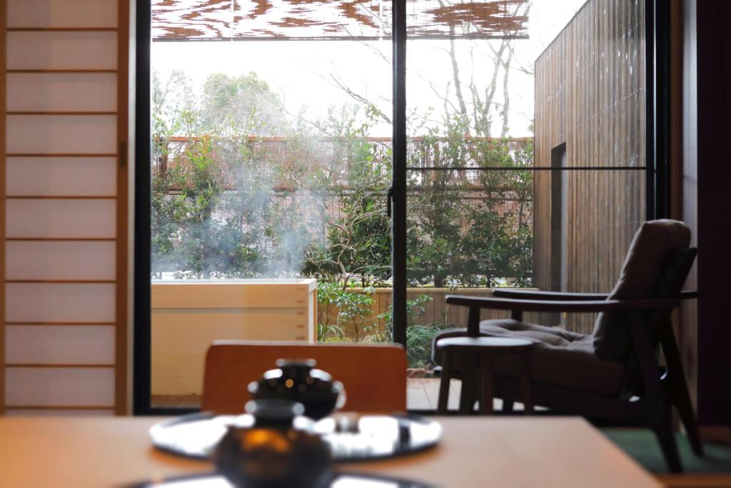 une pièce avec une table et des chaises et une grande fenêtre dans l'établissement Negiya Ryofukaku, à Kobe