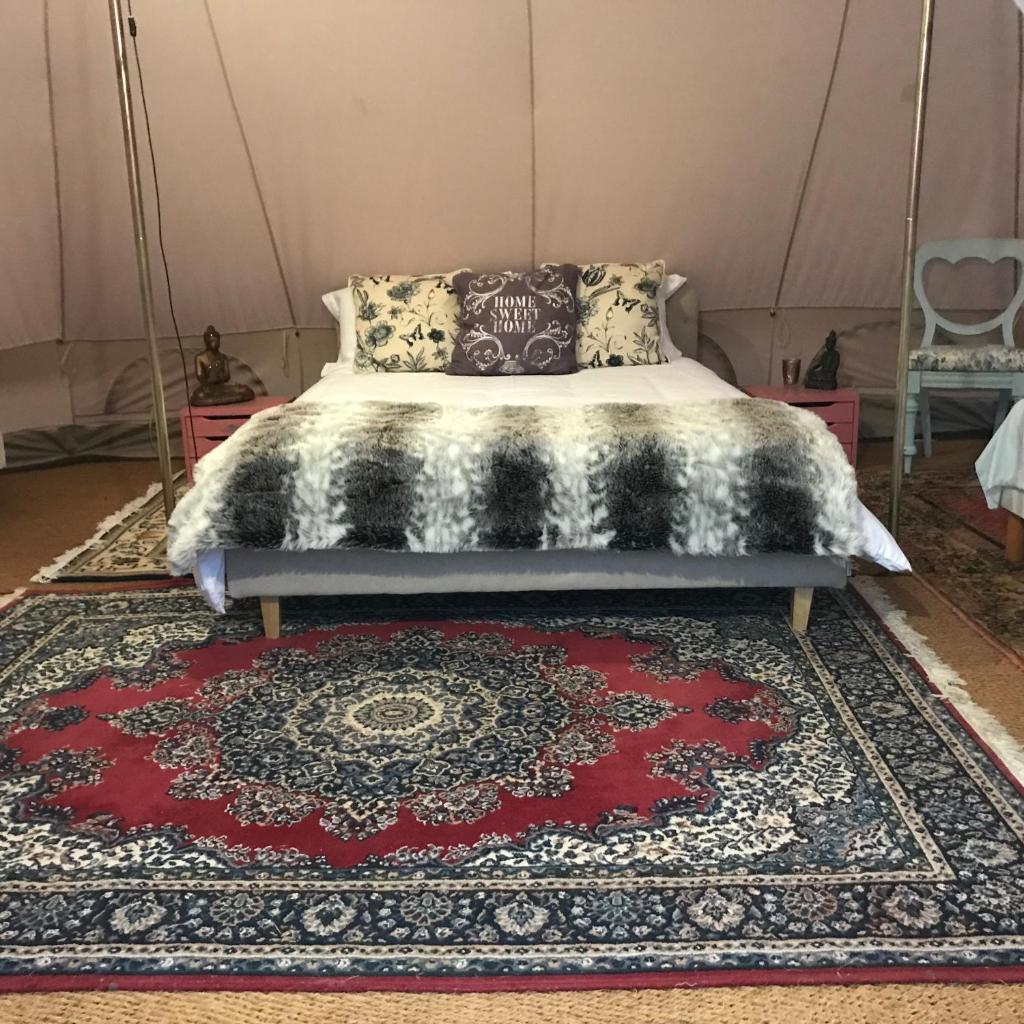 - un lit dans une chambre dotée d'un tapis rouge dans l'établissement French Fields Luxury Glamping Twin Emperor Tent, à Le-Vieux-Cérier 13 autres photos