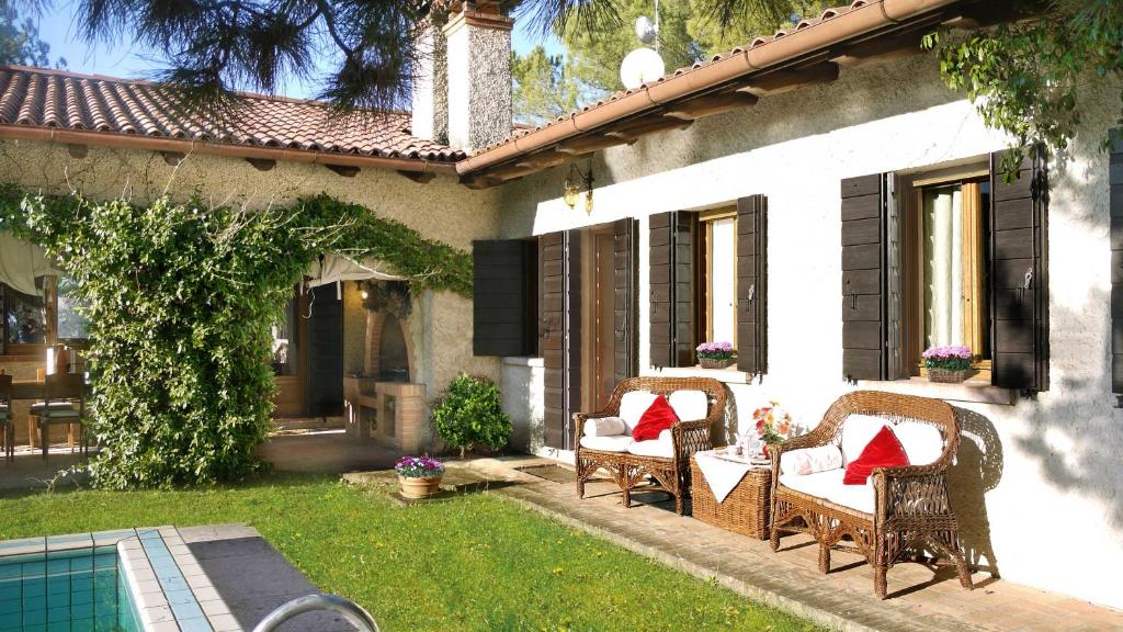 d'une terrasse avec des chaises en osier et des oreillers rouges. dans l'établissement Asolo hills La Cimetta chic villa with pool, à Asolo