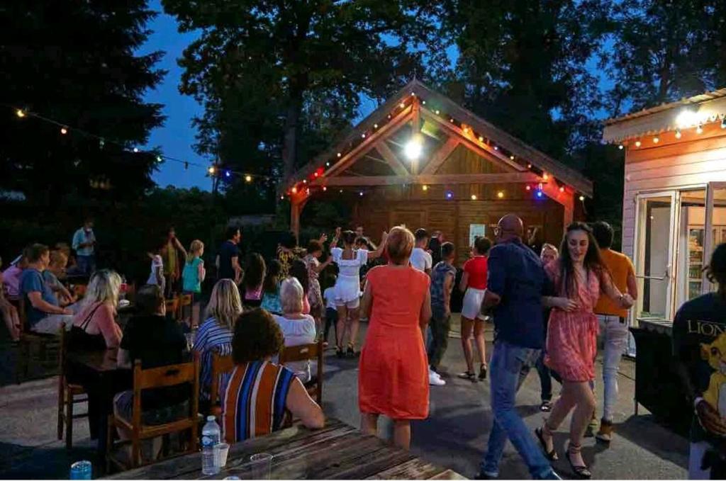 une foule de personnes debout à l'extérieur d'un bâtiment dans l'établissement L'éveil des sens, à Saint-Chéron