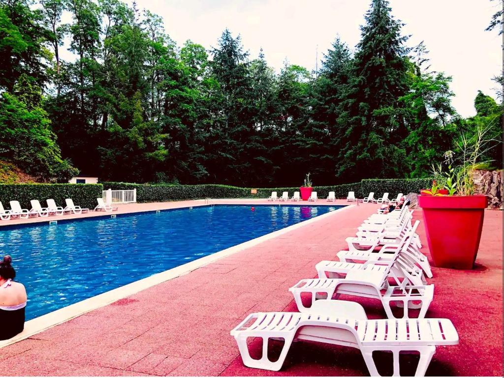 - une rangée de chaises blanches à côté de la piscine dans l'établissement L'indépendant, à Saint-Chéron