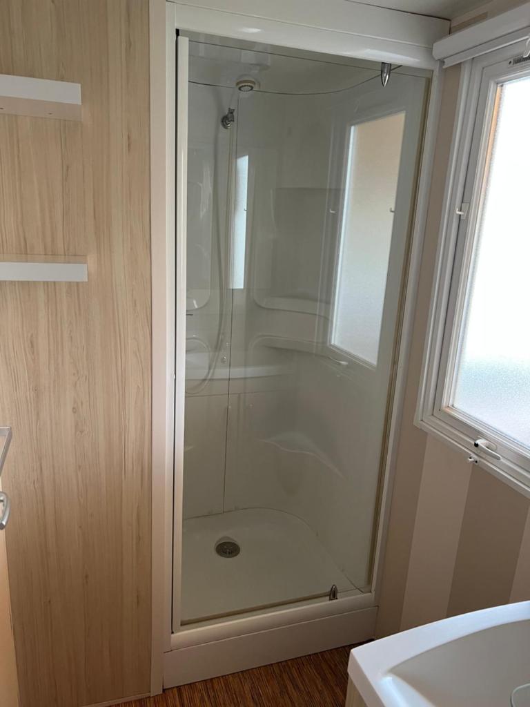une douche avec une porte vitrée dans une salle de bain dans l'établissement Mobilhome 6 CA36, à Vias