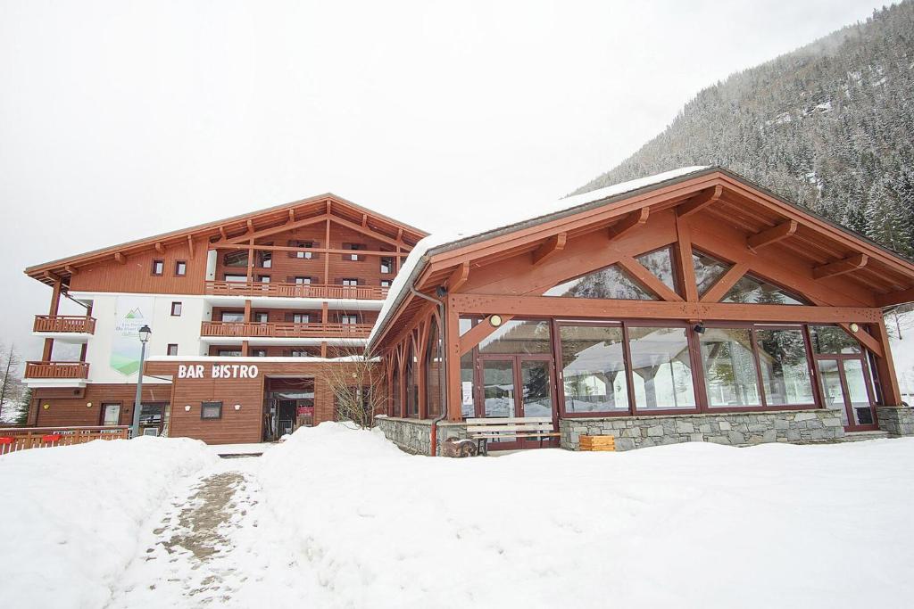 un grand bâtiment avec de la neige devant lui dans l'établissement Le REFUGE DES PORTES DU MONT BLANC, à Vallorcine