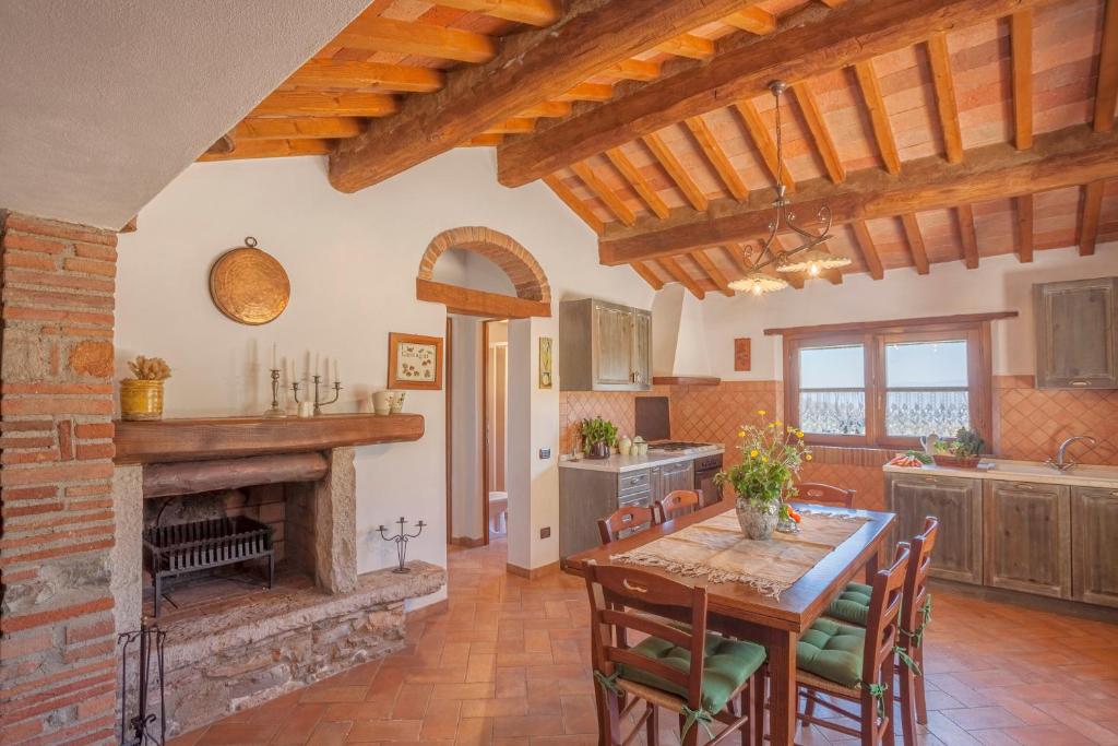 une cuisine avec une cheminée, une table et des chaises dans l'établissement Casa nel Bosco, à Sassetta