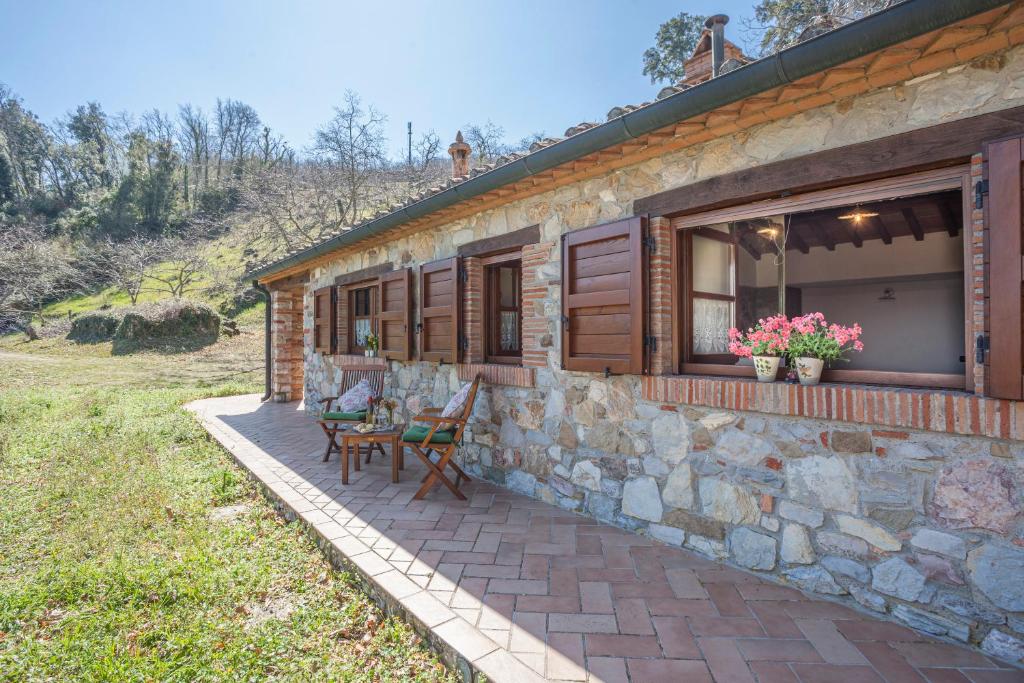 Cette maison en pierre dispose d'une terrasse avec une table et des chaises. dans l'établissement Casa nel Bosco, à Sassetta