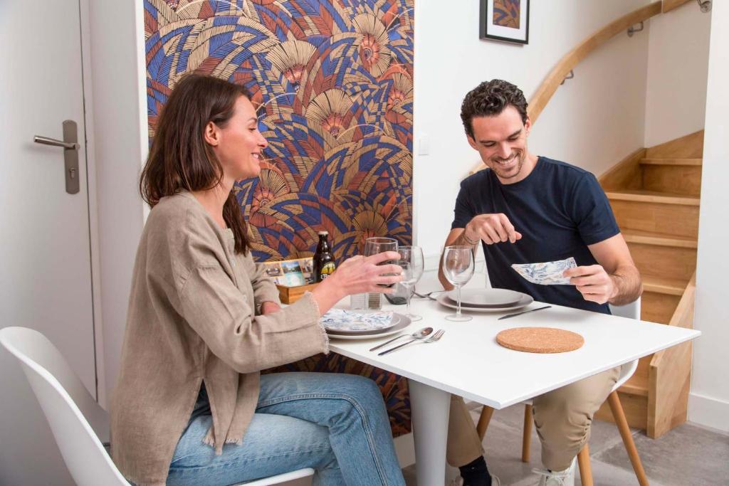 un homme et une femme assis à une table avec des verres à vin dans l'établissement Gîtes de La Vesée, à La Chapelle dʼArmentières