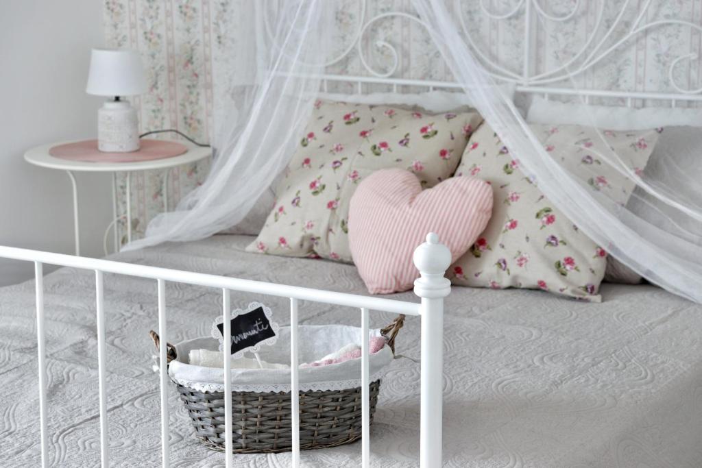 - un lit avec un lit bébé, un oreiller pour le cœur et un panier dans l'établissement Charme Ibleo - Casa di campagna in Sicilia, à Raguse