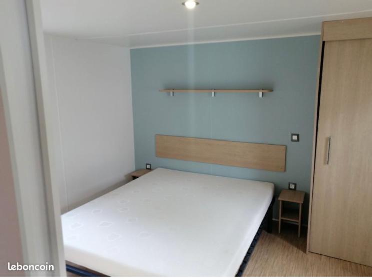 - une chambre avec un lit blanc et un mur bleu dans l'établissement Mobilhome 4/6 pers à 600m de la plage des Conches, à Longeville-sur-Mer