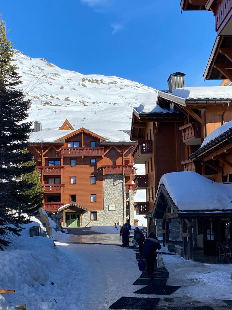 Un groupe de personnes marchant dans une rue enneigée dans l'établissement Le Chamois des Alpages de Reberty ski au pied, aux Menuires