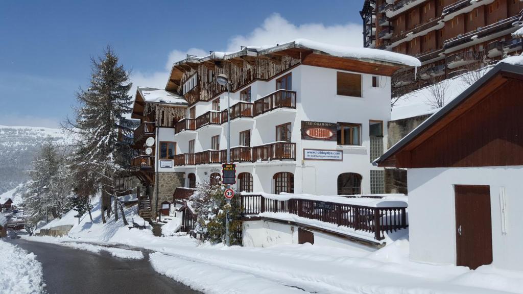 un bâtiment recouvert de neige à côté d'une rivière dans l'établissement Hotel le Chamois, à L'Alpe-d'Huez