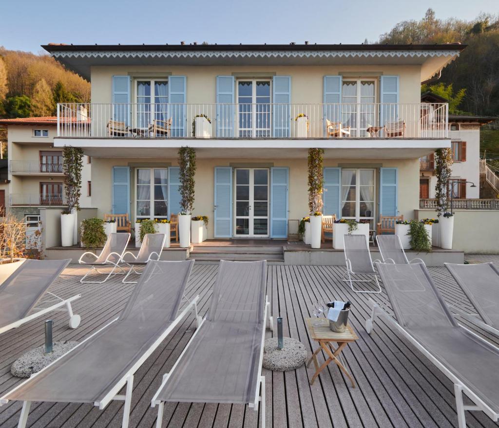 une grande terrasse avec des chaises et une maison dans l'établissement Hotel Villa Aurora, à Lezzeno
