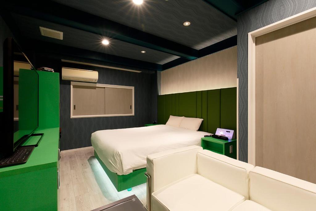 une chambre avec un lit blanc et un mur vert dans l'établissement 555MOTEL -NUMAZU-, à Numazu