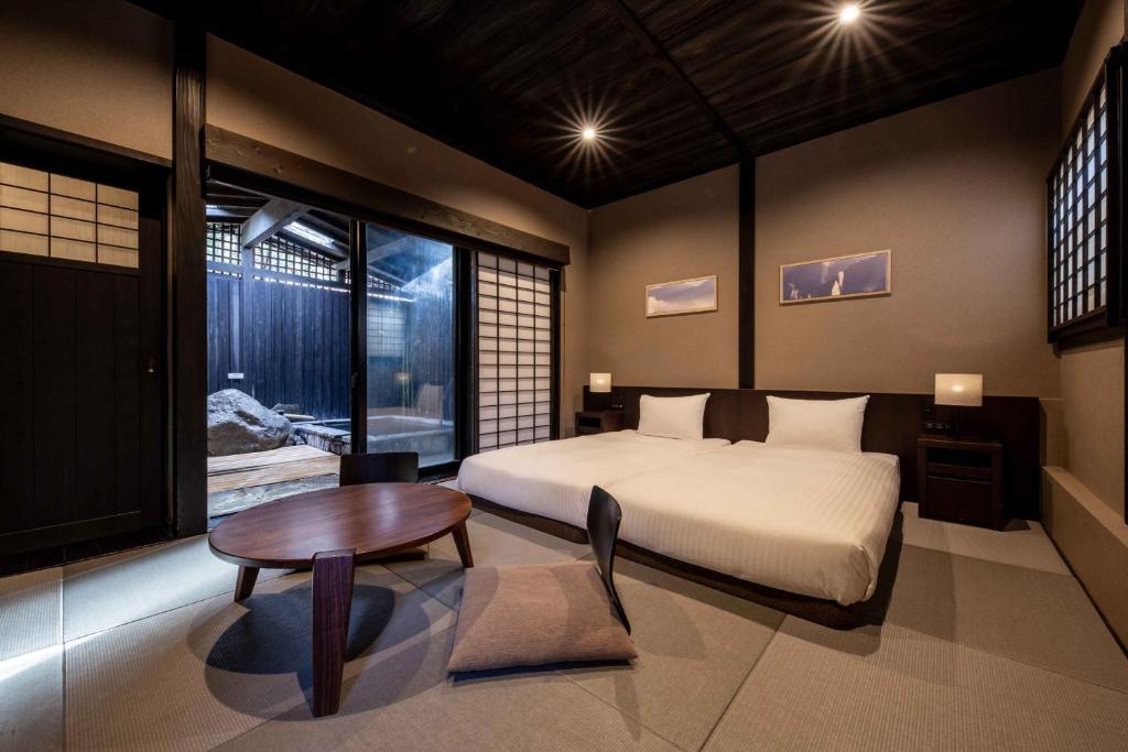 une chambre avec un lit, une table et une fenêtre dans l'établissement Beppu Nagomitsuki, à Beppu