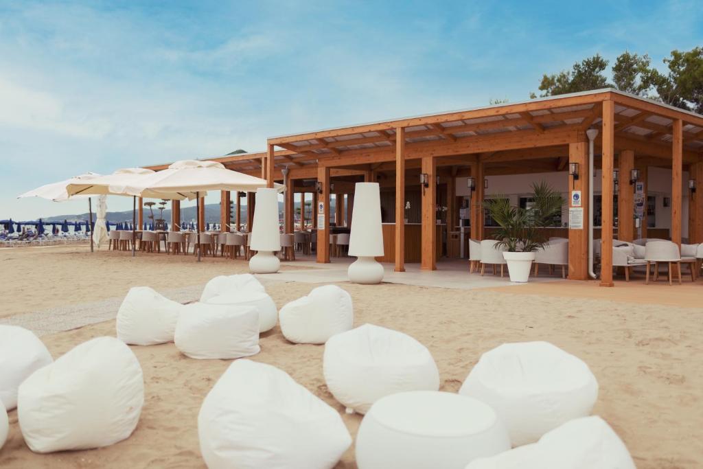 - un bâtiment sur la plage avec des chaises et des parasols blancs dans l'établissement Pizzomunno Vieste Palace Hotel, à Vieste