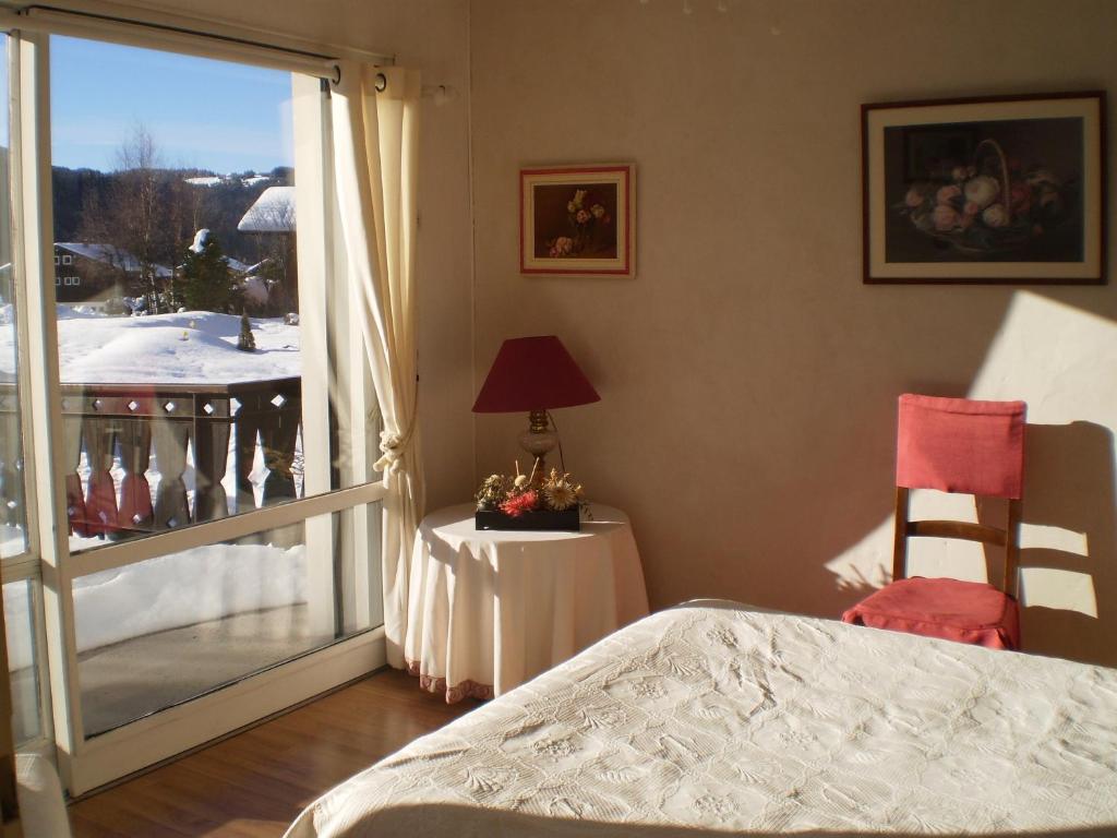 une chambre avec un lit et une vue sur un balcon dans l'établissement Appartement centre-ville au calme Grande Terrasse et Garage, aux Gets