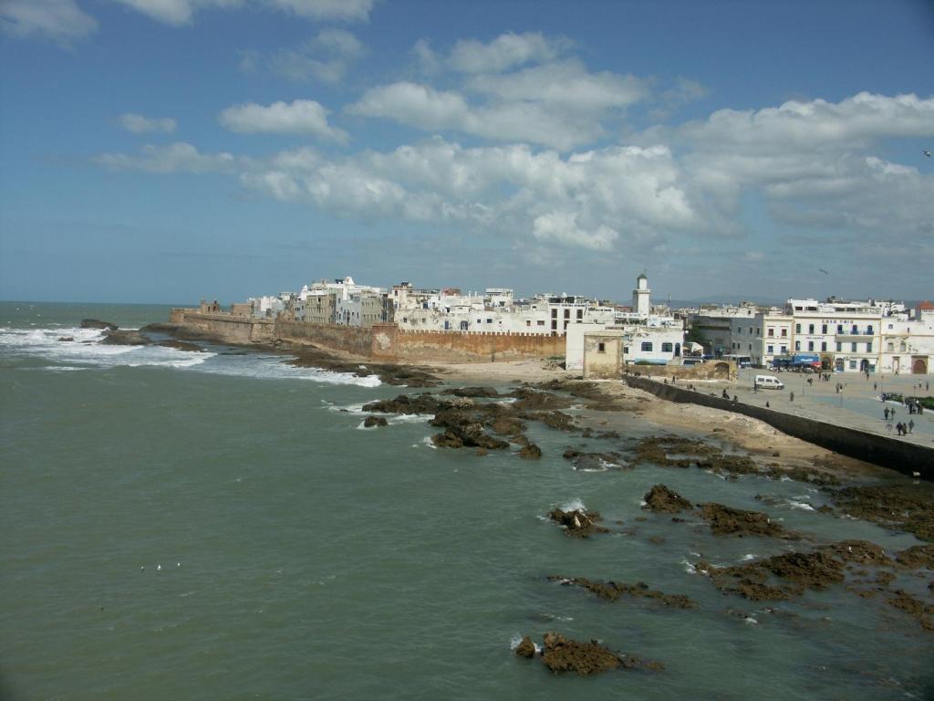 une vue d'une plage avec des bâtiments et l'océan dans l'établissement Dar Ness, à Essaouira
