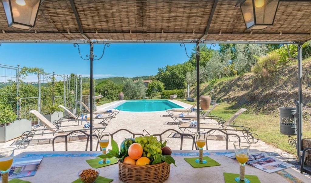 - une table avec une corbeille de fruits et une piscine dans l'établissement Exclusive Villa Parrano - countryside with pool, à Parrano