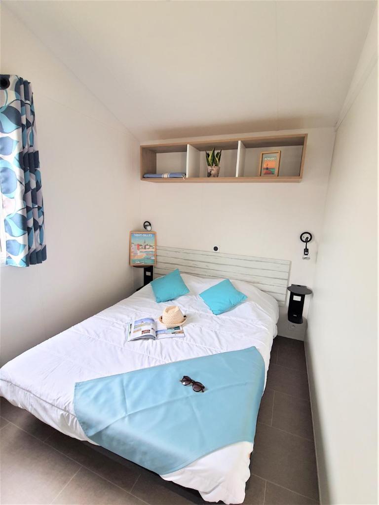 une chambre avec un grand lit blanc avec des oreillers bleus dans l'établissement Camping la Plage, à Saint-Hilaire-de-Riez