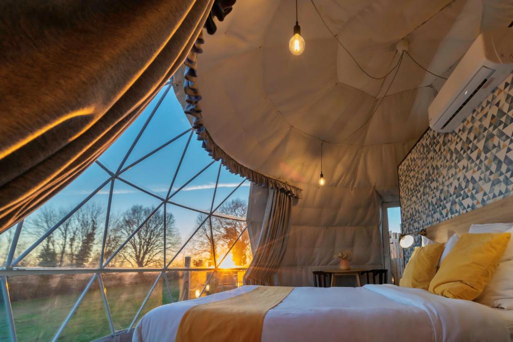 un lit dans une chambre avec une grande fenêtre dans l'établissement Au Champ de l'Insolite, à Miers