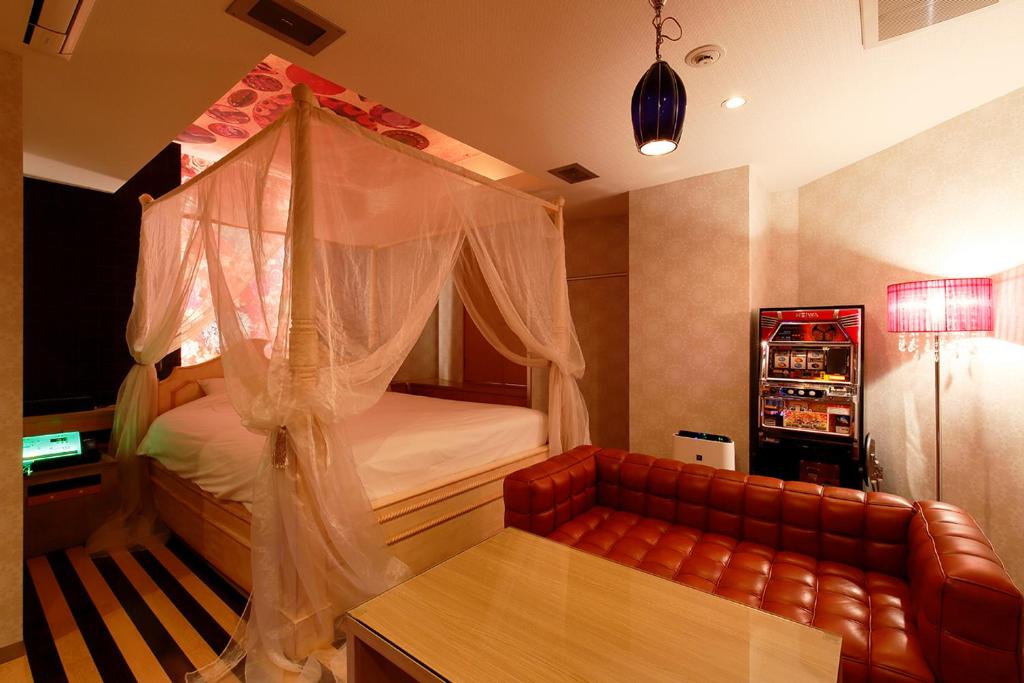une chambre avec un lit à baldaquin et un canapé dans l'établissement HOTEL555 錦糸町, à Tokyo