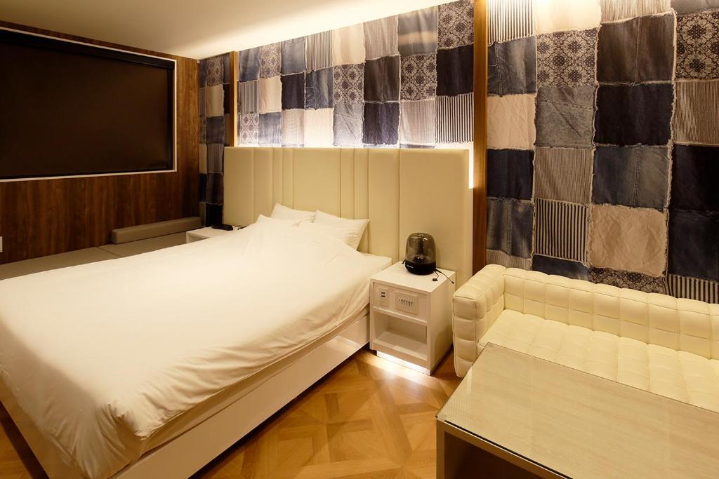 une chambre avec un grand lit blanc et un canapé dans l'établissement KNOWS HOTEL, à Numazu