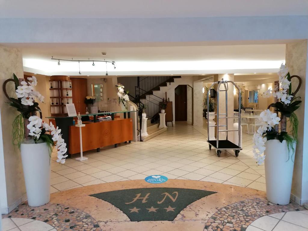 un hall d'entrée avec deux vases blancs contenant des fleurs. dans l'établissement Hotel Nordic, à Bellaria-Igea Marina 125 autres photos