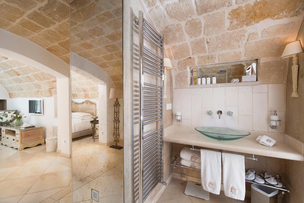 une salle de bain avec un lavabo et une chambre avec un lit dans l'établissement Hotel Don Ferrante, à Monopoli