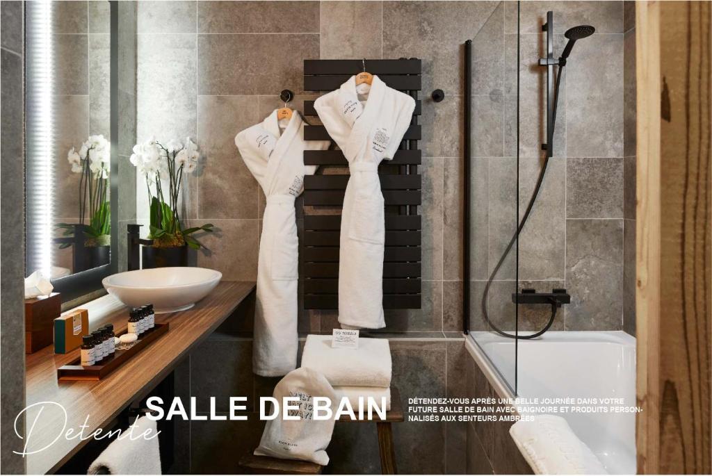 une salle de bain avec un peignoir blanc sur un support dans l'établissement Ecrin Blanc Resort Courchevel - Aquapark, à Courchevel
