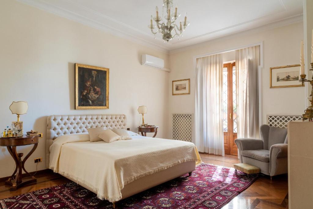 une chambre blanche avec un lit et une chaise dans l'établissement Palazzo P D'ajmo - Dimora Storica, à Lecce 37 autres photos