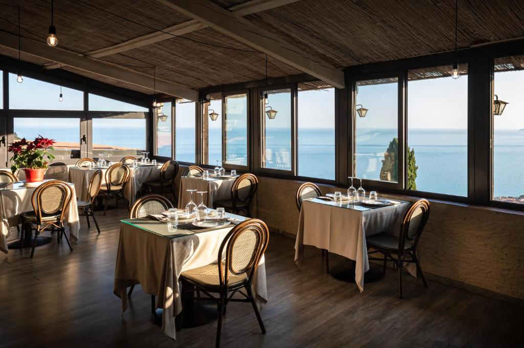un restaurant avec des tables, des chaises et des fenêtres dans l'établissement Locanda Antica Osteria Saracena del Bergallo, à Borgio Verezzi