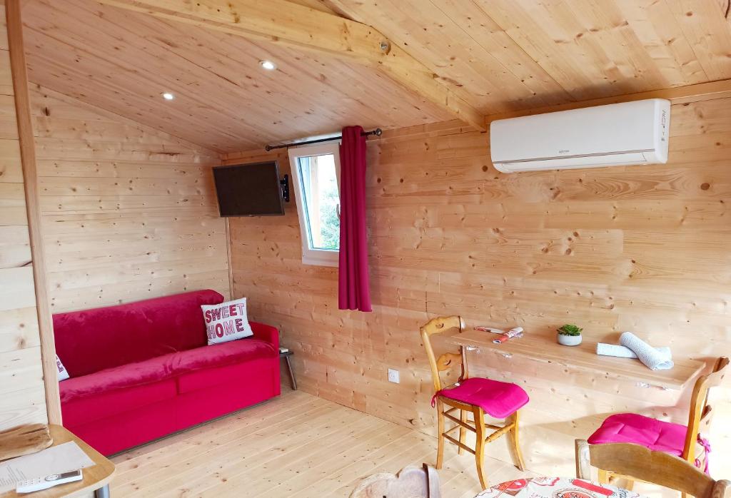une chambre avec un canapé rouge dans une cabane en bois dans l'établissement Yourte A bourlon, à Bourlon