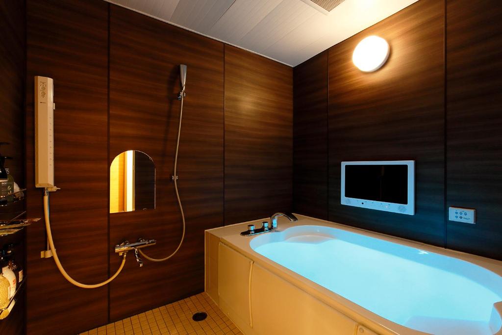 une salle de bain avec une baignoire et une télévision au mur dans l'établissement HOTEL 555 Air, à Higashine 14 autres photos