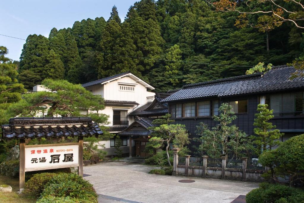un bâtiment avec un panneau devant une montagne dans l'établissement Motoyu Ishiya, à Kanazawa