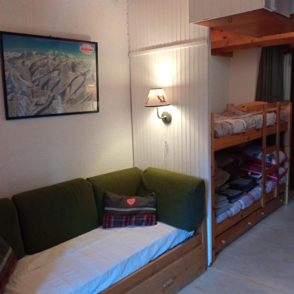 Cette chambre comprend un canapé vert et des lits superposés. dans l'établissement Appartement dernier étage au pied des pistes HIRMENTAZ, à Bellevaux