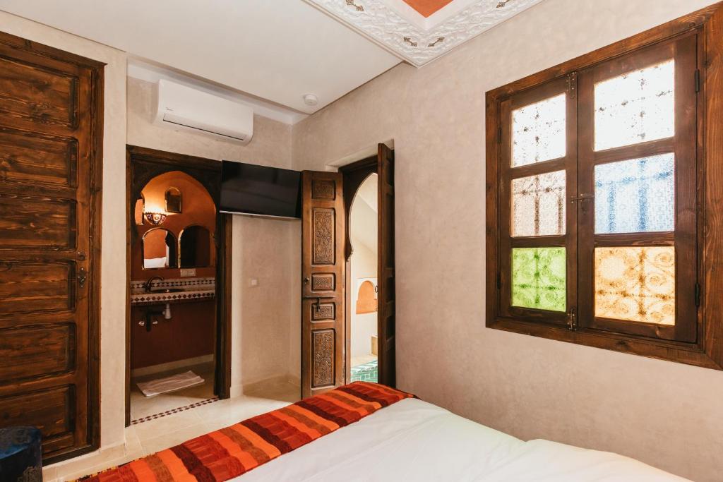 une chambre avec un lit et une fenêtre dans l'établissement L'Emeraude de la Médina, à Marrakech