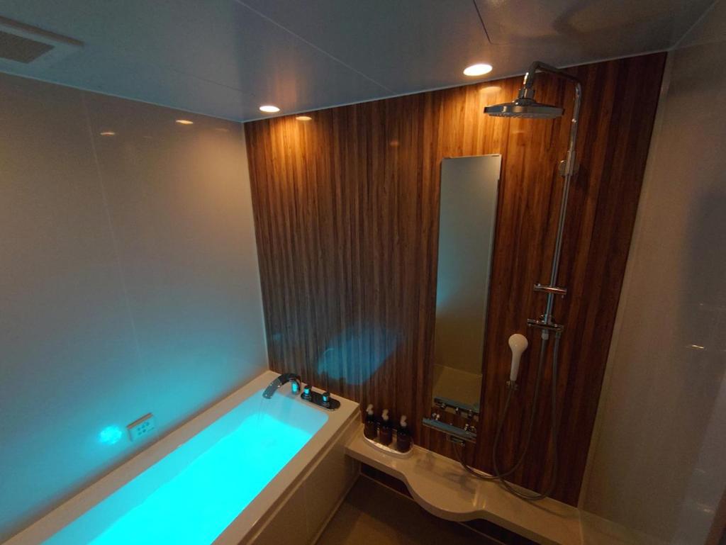 une salle de bain avec une baignoire avec un miroir dans l'établissement Utovilla HOTEL555 沼津店, à Numazu