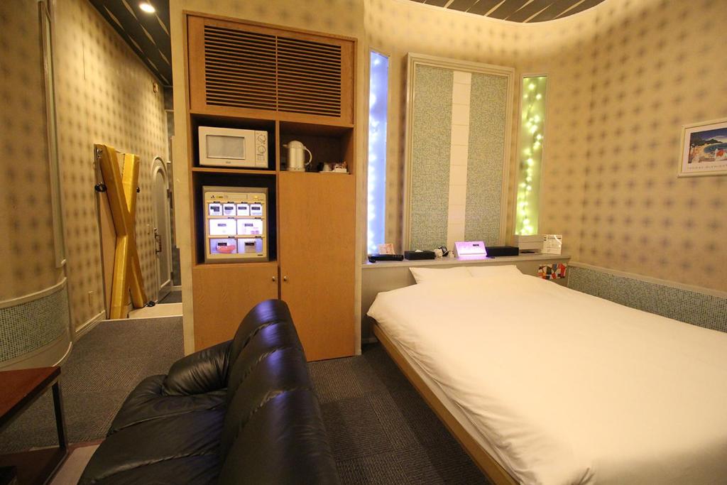 une chambre avec un lit et un canapé dans l'établissement Utovilla HOTEL555 沼津店, à Numazu