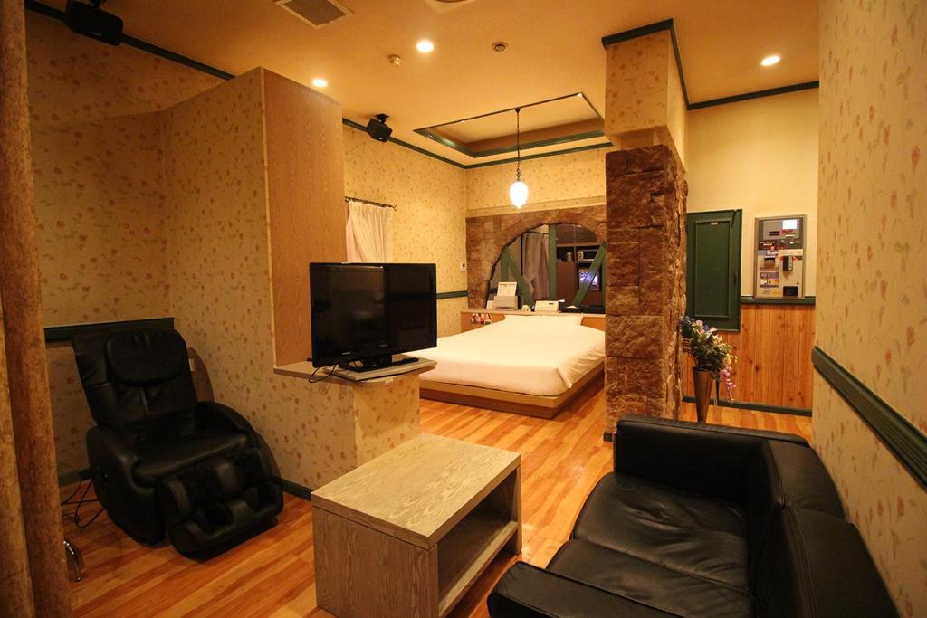 - un salon avec une chambre dotée d'un lit et d'une chaise dans l'établissement Utovilla HOTEL555 沼津店, à Numazu
