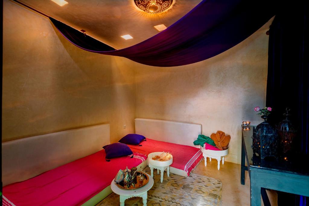 - une chambre avec un lit rouge et deux tables dans l'établissement Riad Ines Home, à Marrakech
