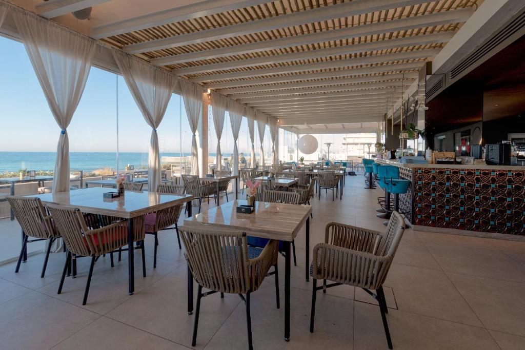 un restaurant avec des tables et des chaises et une vue sur l'océan dans l'établissement Il Fogliano Hotel New Life, à Latina