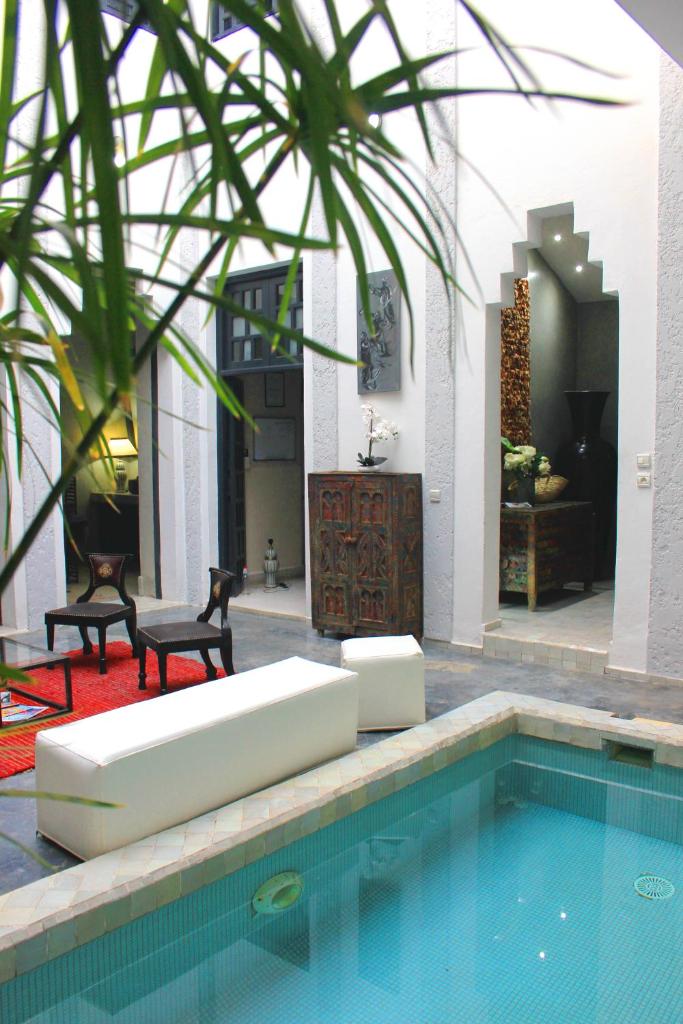 - une piscine avec un canapé et des chaises à côté d'une maison dans l'établissement Riad Heva, à Marrakech