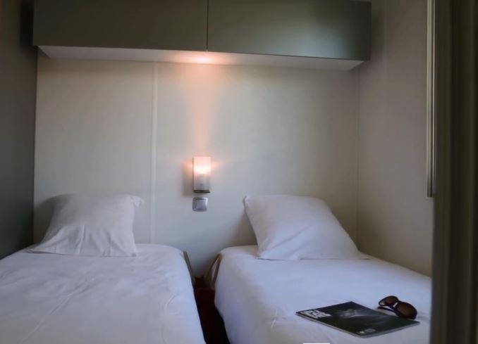 - 2 lits dans une chambre d'hôtel avec un livre sur le lit dans l'établissement Camping maeva Escapades Au P'tit Bonheur, à Peyrillac-et-Millac